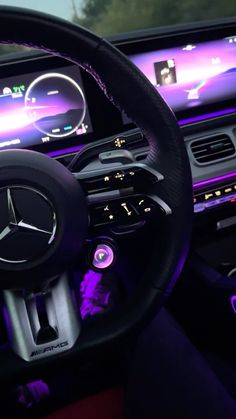 the steering wheel and dashboard of a mercedes benz - benz car, with purple lighting