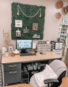 a desk with a computer on it in front of a green wall and several other items