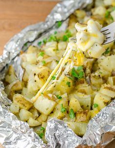 a fork is lifting up some food out of the foil