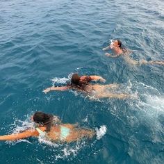 three people swimming in the ocean together