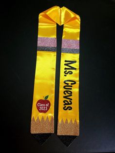 two yellow graduation sashes with an apple on them