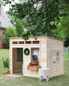 a small wooden shed sitting on top of a lush green field next to a tree