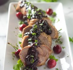 a white plate topped with meat covered in cranberry sauce and garnish