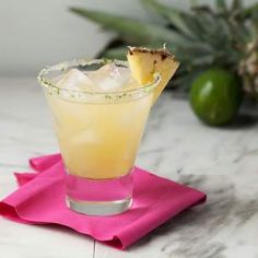 a pineapple margarita sitting on top of a pink napkin