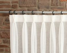 a white curtain hanging on the side of a brick wall