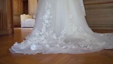 the back of a wedding dress on display in a room with wooden floors and walls