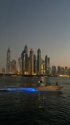 a speed boat in the water with a city skyline in the backgrouds