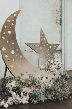 two metal stars and a crescent on top of some cotton flowers in front of a white brick wall