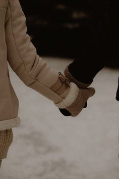 two people holding hands in the snow with one person's hand on the ground