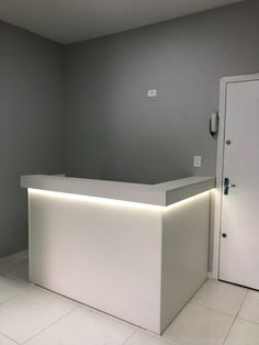 an empty white reception counter with lights on the front and back walls, in a gray room