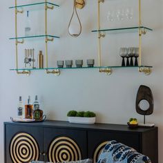 a living room filled with furniture and lots of glass shelves on the wall above it