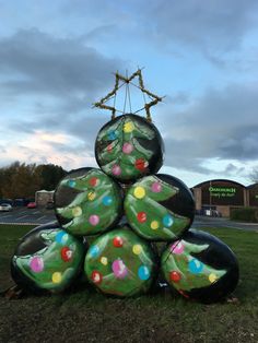 a large christmas tree made out of balloons on the ground in front of a building