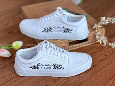 two white shoes with black and white flowers on the soles are sitting on a wooden table