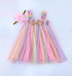 ♥ Pastel Rainbow Dress ♥  This stunning tulle dress is sure to be a special addition to your little one's wardrobe. The soft rainbow tulle with gold foil stars truly dazzles! It's perfect for cake smash photos. Fully lined. The headband is soft and stretchy ♥ ORDER TRACKING All orders shipped to the US include tracking. The free shipping option for this item within Canada does not offer tracking. If that is a feature you require please contact me BEFORE ordering for a quote, thanks! RUSH ORDERS 2nd Birthday Girl, Star Outfit, Rainbow Tutu, Girl 2nd Birthday, Floral Headband, Girl Rainbow, Cake Smash Photos, Rainbow Dress, Orders Shipped