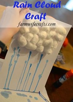 a hand holding up a paper with blue paint on it and the words rain cloud craft