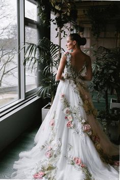 a woman in a wedding dress looking out the window