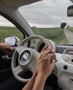 a person driving a car on a road with fields in the background