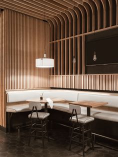 the interior of a restaurant with wooden walls and booths, white benches and stools