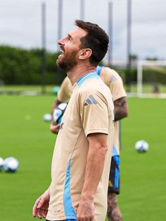 a man standing on top of a lush green field next to a soccer ball covered field