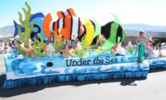 the float is decorated with colorful fish and sea creatures for an ocean themed parade on the street