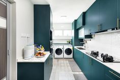 a long narrow kitchen with green cabinets and white counter tops, along with a washer and dryer