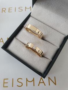 two gold rings sitting in a black box