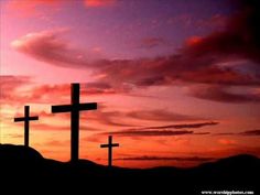 three crosses are silhouetted against an orange and purple sky with clouds in the background