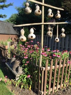 a garden with lots of flowers growing in the ground and hanging from a wooden pole