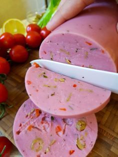 a person cutting up some food on top of a cutting board next to tomatoes and lemons