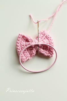 a pink crocheted bow tie hanging from a string