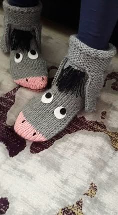 the legs and feet of someone wearing knitted slippers with horse faces on them