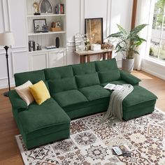 a large green couch sitting on top of a wooden floor next to a white rug