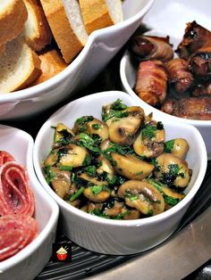 three white bowls filled with food on top of a metal tray next to bread and meat