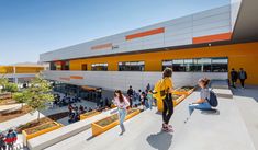 people are walking around in front of an orange and white building