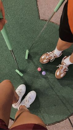 two people are playing golf on the green carpeted area with balls and tees