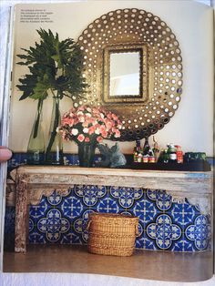 a table with flowers and vases on top of it in front of a mirror