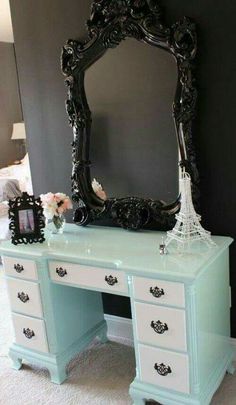 a desk with a mirror and flowers on it in front of a wall mounted eiffel tower