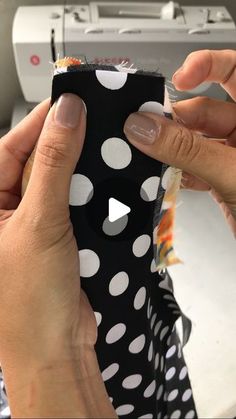 two hands holding a black and white polka dot case