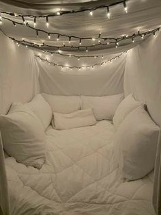 a bed with white sheets and lights on the ceiling is made up to look like a tent