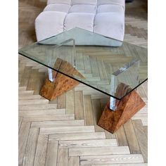 a glass and wood coffee table sitting on top of a wooden floor