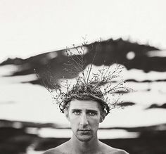 black and white photograph of a man with no shirt wearing a flower crown on his head