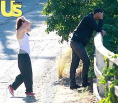 a man and woman walking down a road next to each other with their hands on their head