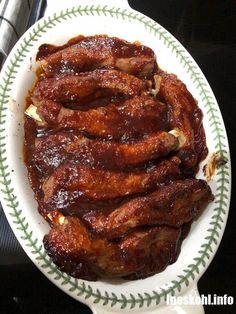 a white plate topped with meat covered in sauce on top of a stove burner