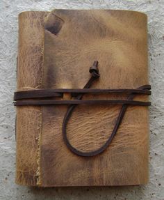 an old leather journal with a cord on the cover is sitting on a white surface