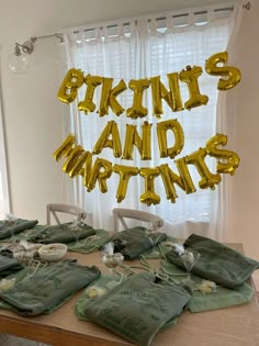 the table is set up with many bags and gold foil balloons that spell out words