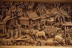 an intricately carved wood panel depicting people and animals in a village with palm trees