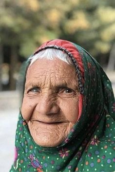 an old woman wearing a headscarf smiles at the camera