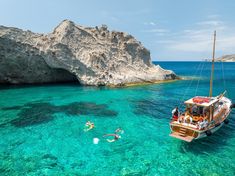 people swimming in clear blue water next to a boat