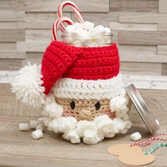 a crocheted santa claus jar filled with candy canes and marshmallows