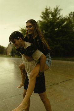 two people are playing in the rain with an umbrella and one person is on his back